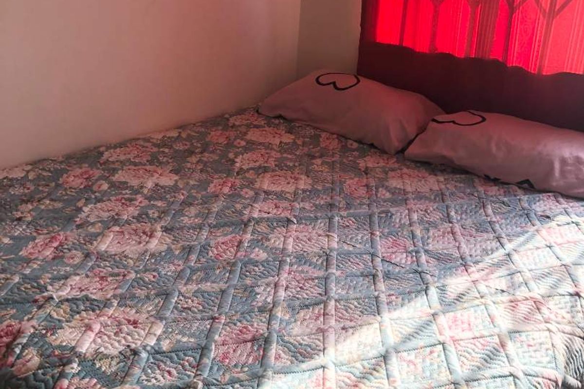 A bedroom featuring a window with a fitted security gate, providing natural light and basic security.