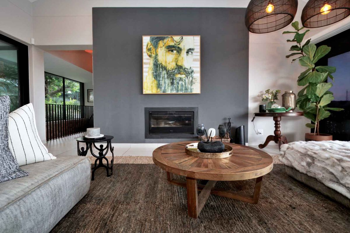 A modern living room featuring a built-in fireplace set into a dark grey feature wall, with large sliding glass doors leading to an outdoor area.