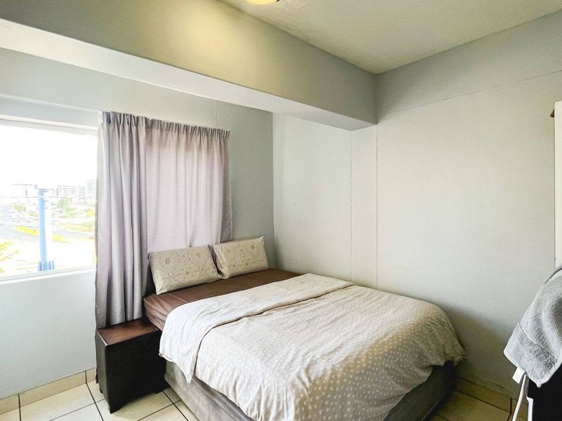 A functional bedroom featuring tiled flooring and a window providing natural light.