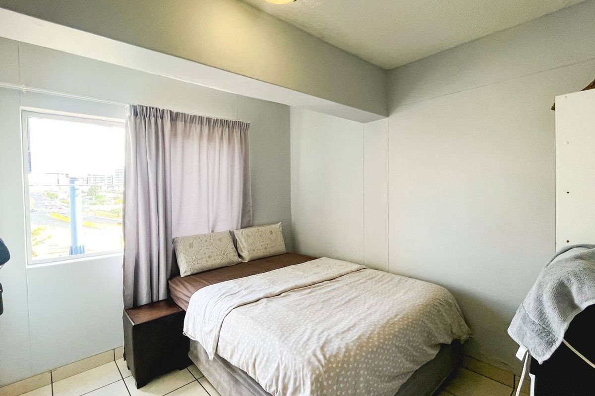 A functional bedroom featuring tiled flooring and a window providing natural light.
