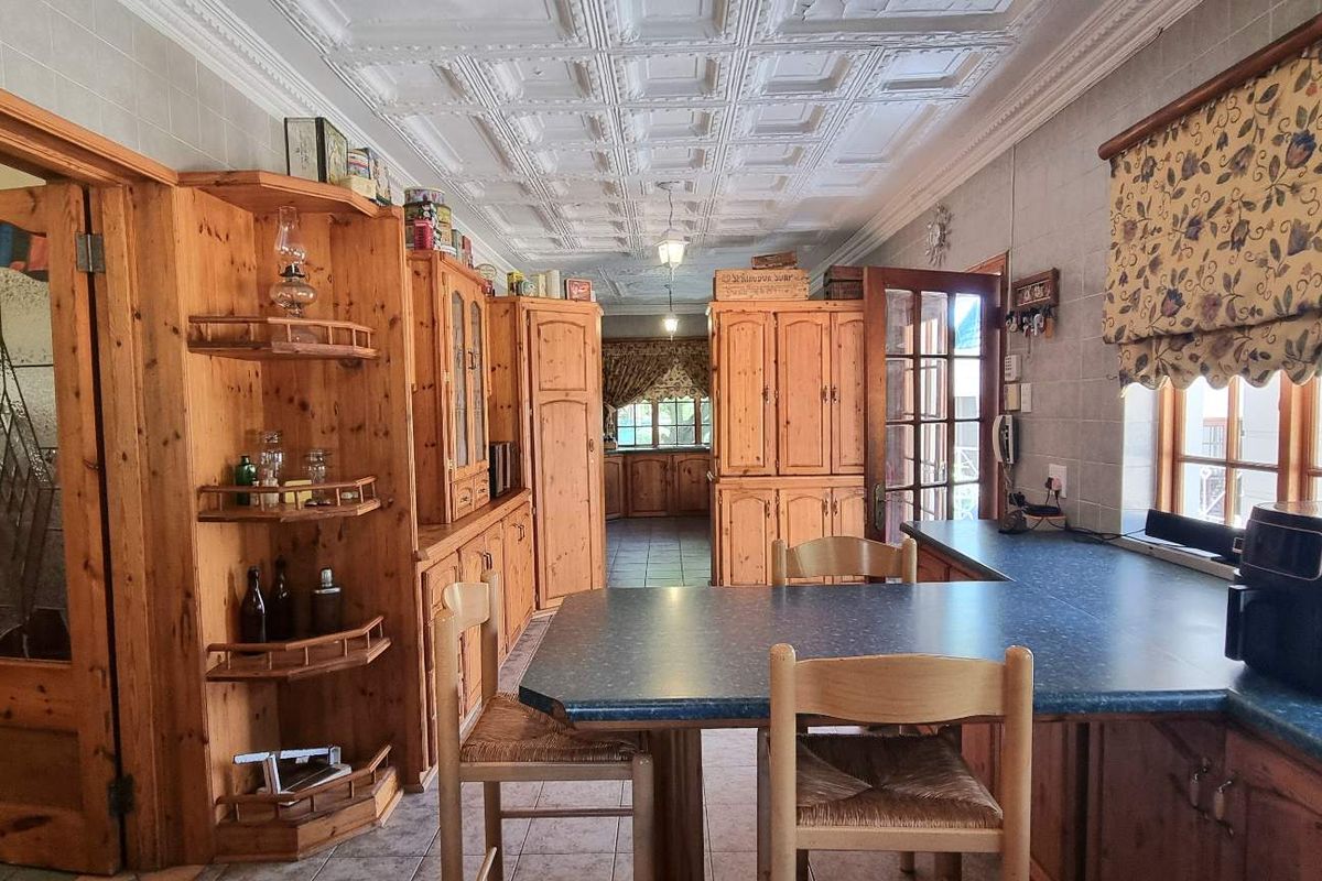 A traditional kitchen featuring extensive timber cabinetry, tiled walls, and a decorative pressed metal ceiling, offering a classic aesthetic with functional layout.