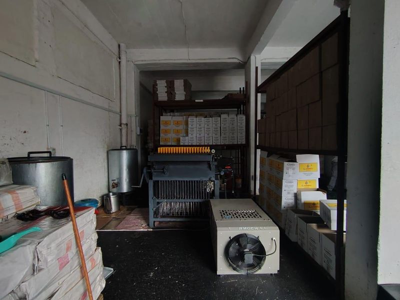 Industrial utility space featuring heavy machinery, metal storage shelving, and exposed infrastructure, suitable for manufacturing or storage operations.