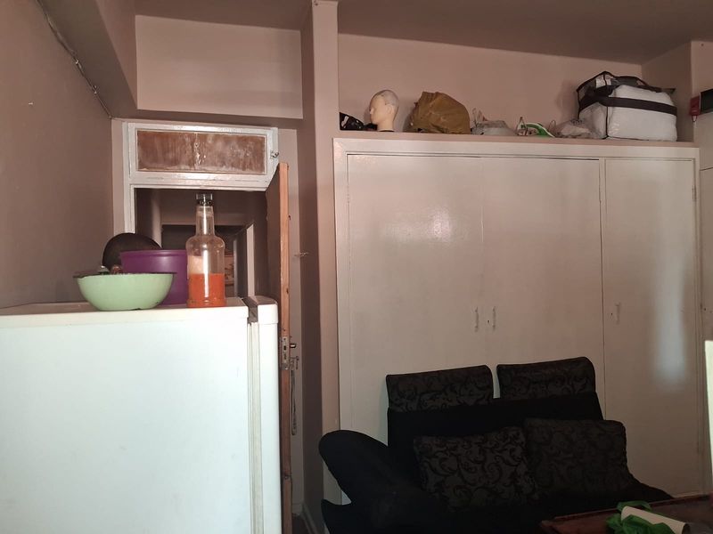 A bedroom featuring built-in cupboards with visible wear and tear on the surrounding door frame.