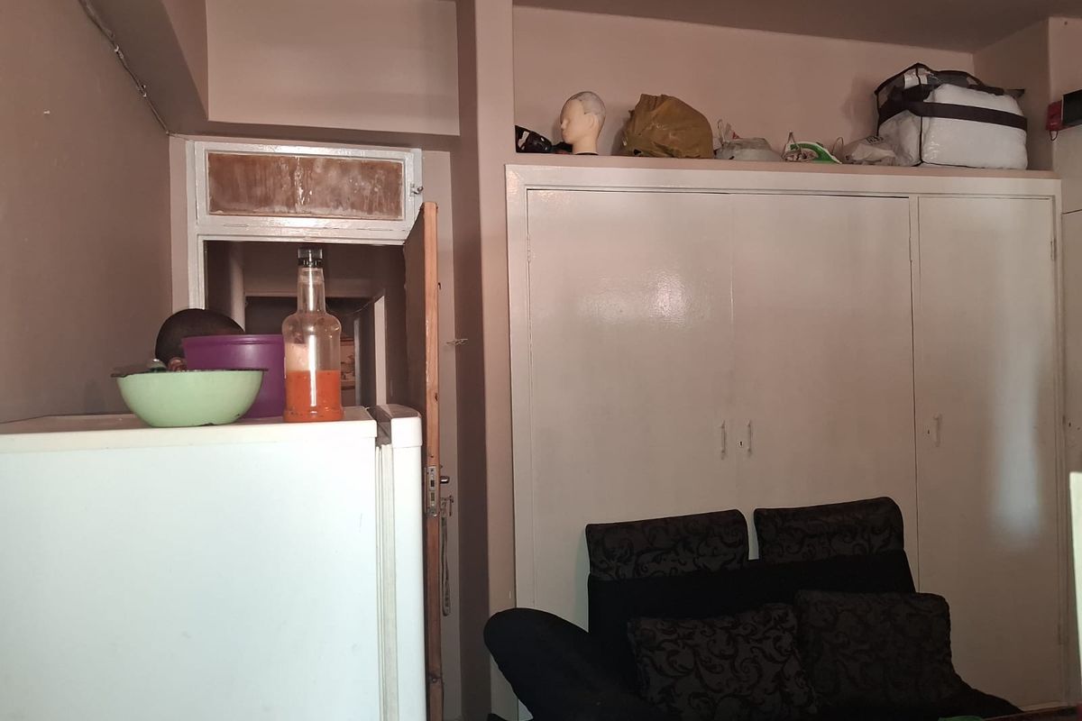 A bedroom featuring built-in cupboards with visible wear and tear on the surrounding door frame.