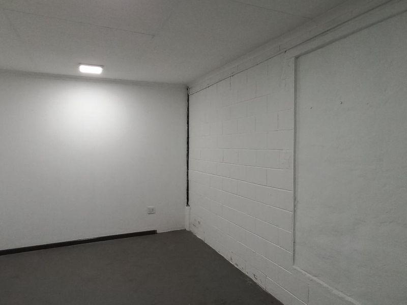 A functional, empty industrial utility space featuring painted block walls, recessed ceiling lighting, and durable flooring, suitable for storage or office use.