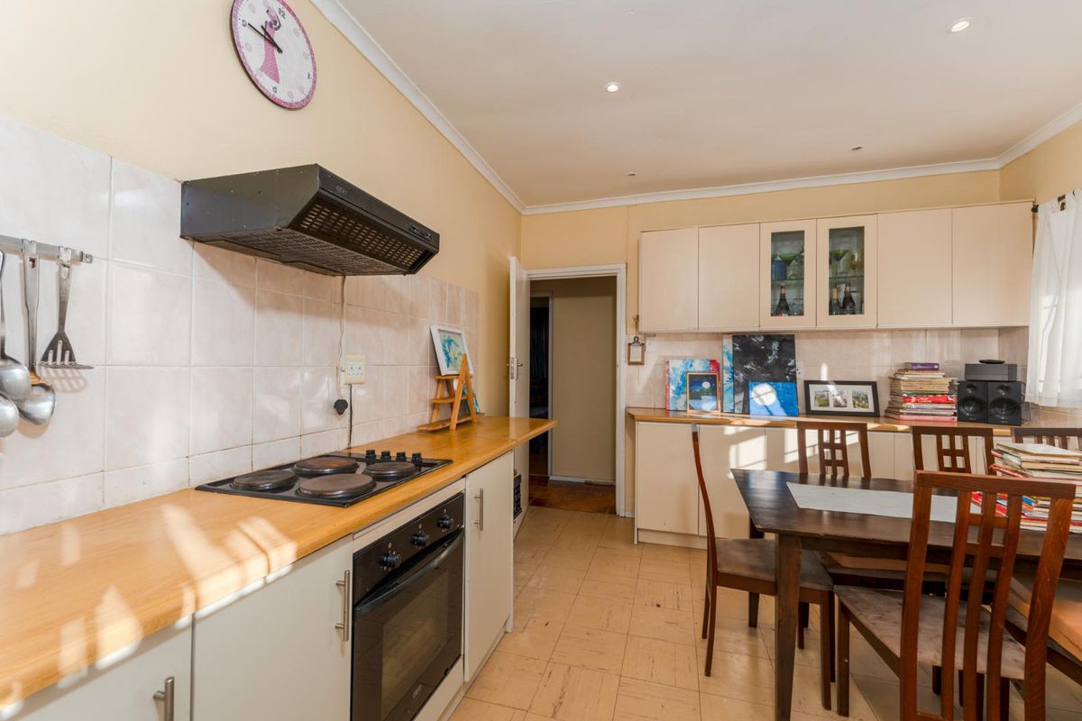 A functional kitchen featuring built-in cabinetry, a wooden countertop, integrated oven and hob, and an extractor fan, with an adjacent dining area.
