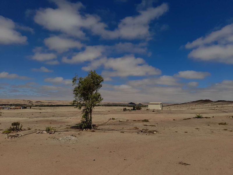 A wide-angle view of the expansive arid landscape on the small holding, featuring natural terrain and perimeter fencing.