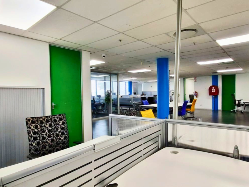 Open-plan office space featuring suspended ceilings, recessed lighting, and glass partitions, providing a functional and bright professional work environment.