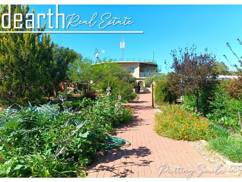 A view of a well-maintained garden with a brick-paved pathway leading towards the main building structure in a retirement village setting.