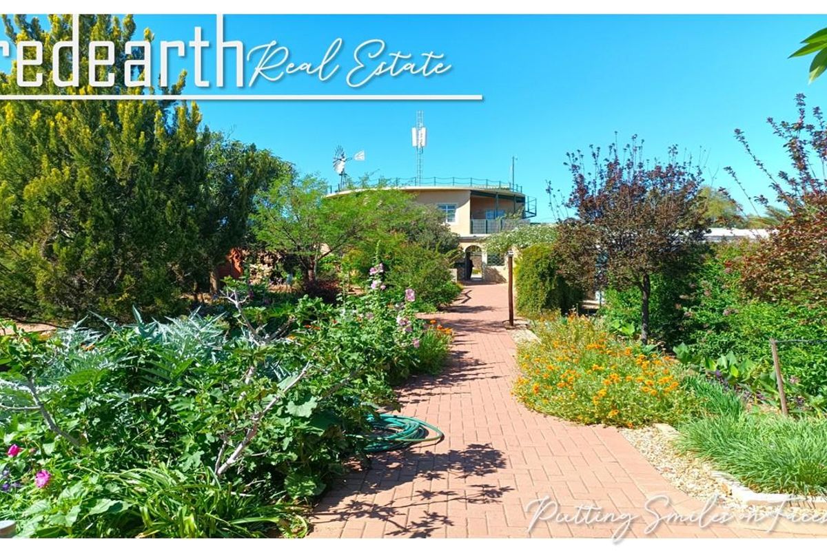 A view of a well-maintained garden with a brick-paved pathway leading towards the main building structure in a retirement village setting.