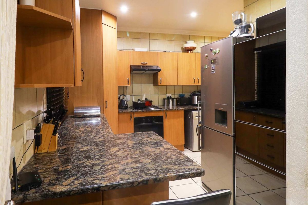 A functional kitchen featuring wooden cabinetry, granite countertops, tiled backsplash, and built-in oven with extractor fan.