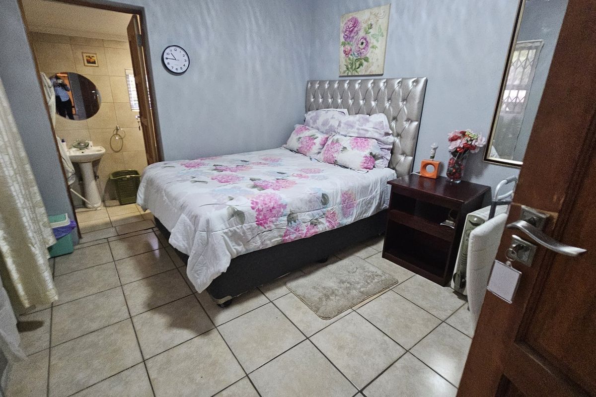 A bedroom featuring tiled flooring and direct access to an en-suite bathroom with a pedestal basin.