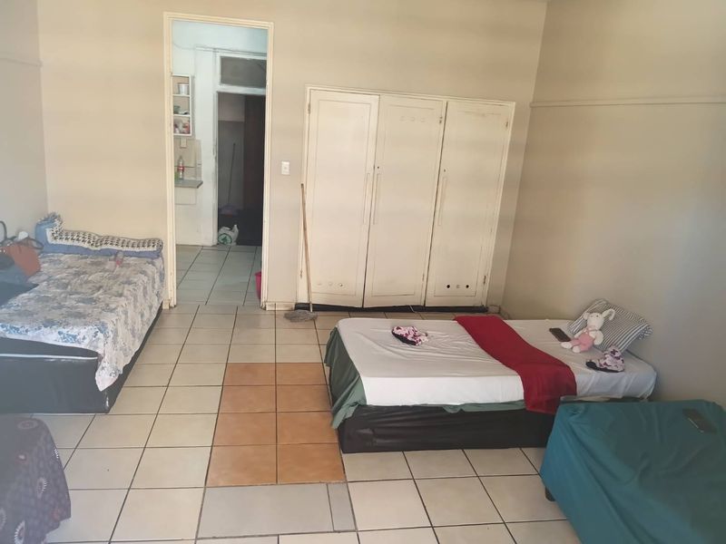 A bedroom featuring built-in cupboards and tiled flooring, offering a functional space with potential for cosmetic updates to improve its overall appeal.