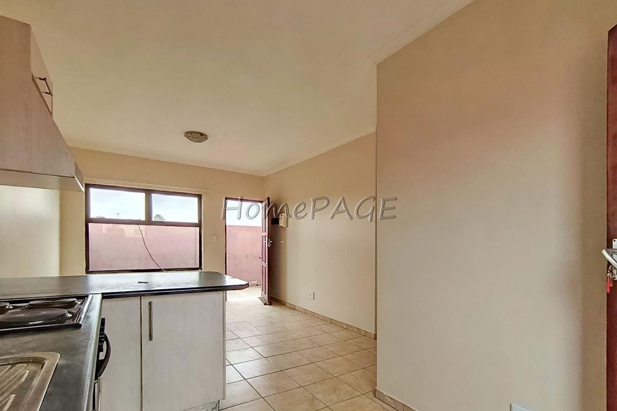 A functional kitchen area featuring built-in cabinetry, a hob, and tiled flooring, with direct access to an outdoor space.