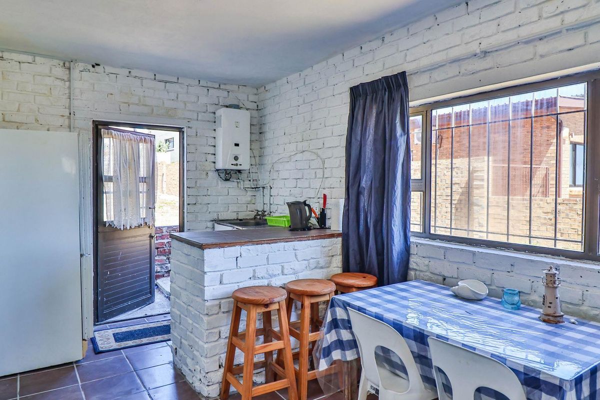 A functional kitchen area featuring white-painted brick walls, a breakfast bar, and direct access to the exterior.