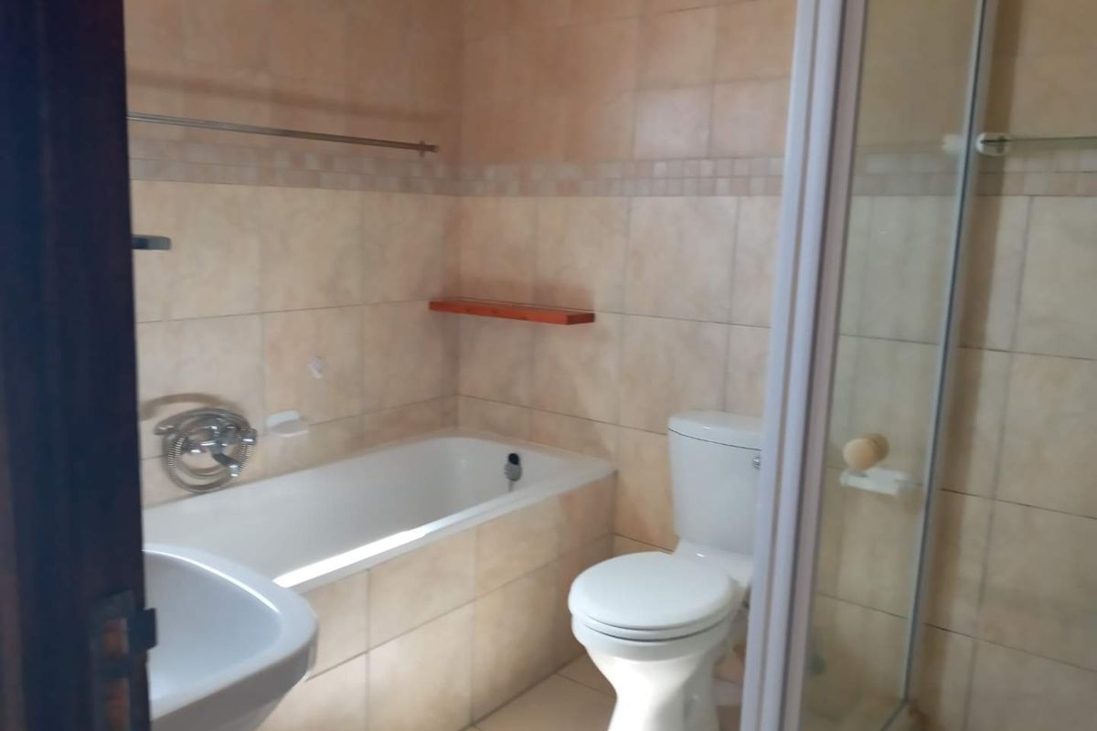 A functional bathroom featuring a bathtub, separate shower enclosure, and toilet with neutral wall tiling.