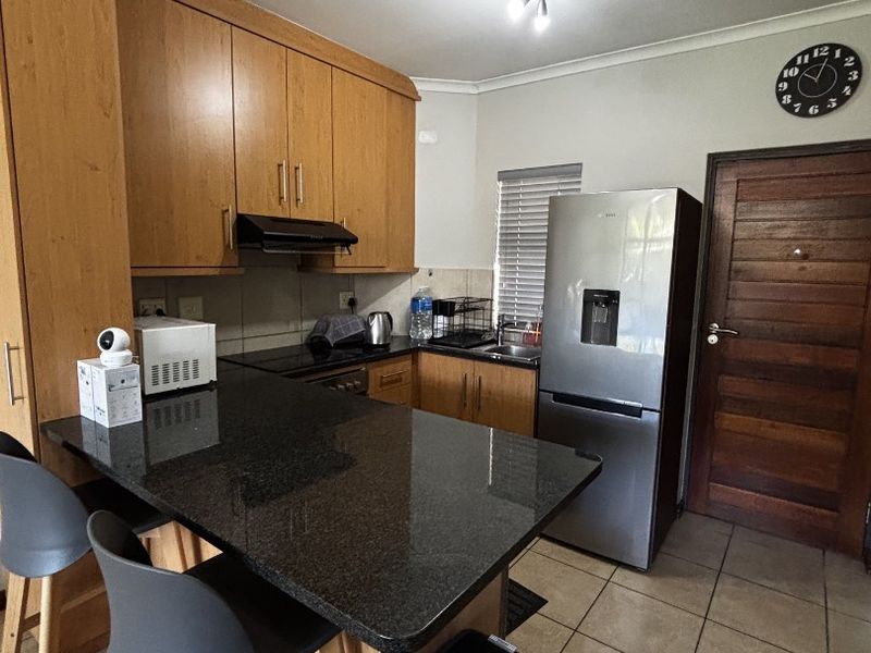A functional kitchen featuring wooden cabinetry, granite countertops, a breakfast bar, and tiled flooring, providing a practical layout for daily use.