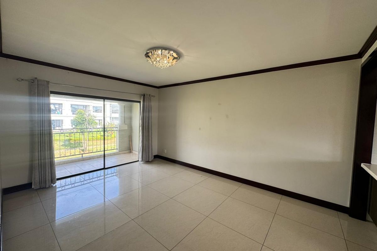Spacious living area featuring large sliding glass doors leading to a balcony, polished tile flooring, and a decorative ceiling light fixture.
