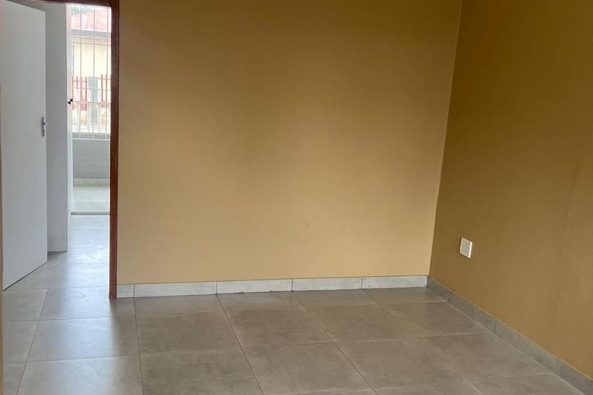 An empty living area featuring neutral wall paint and large format floor tiles, providing a clean and versatile space for interior design.
