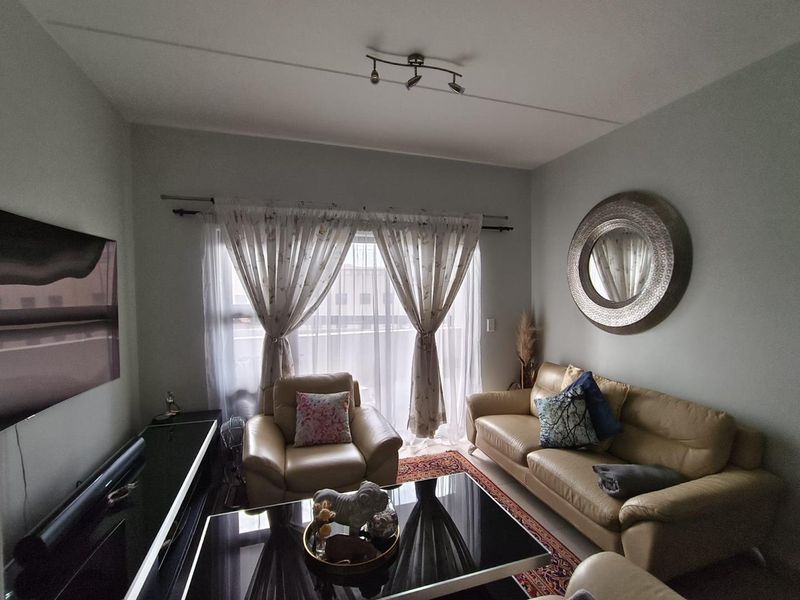 A comfortable living room featuring a sliding glass door with natural light, neutral wall tones, and modern ceiling spotlighting.