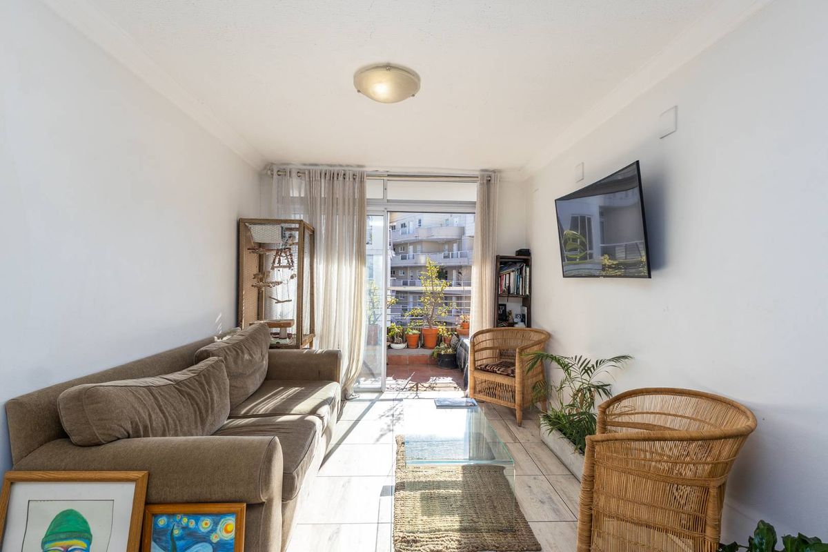 A bright living room featuring tiled flooring and a sliding glass door that opens onto a balcony, providing natural light and outdoor access.