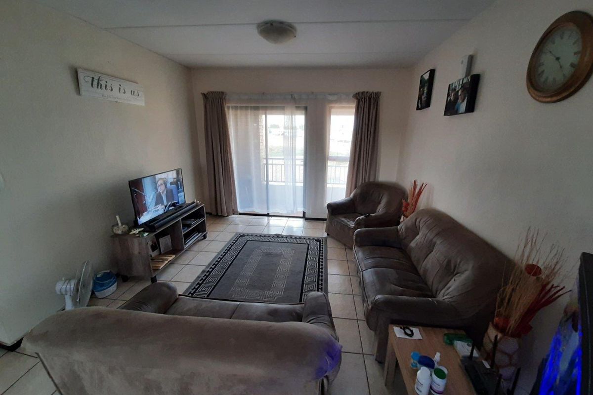 A comfortable living room featuring tiled flooring and sliding glass doors that provide access to an outdoor balcony area.