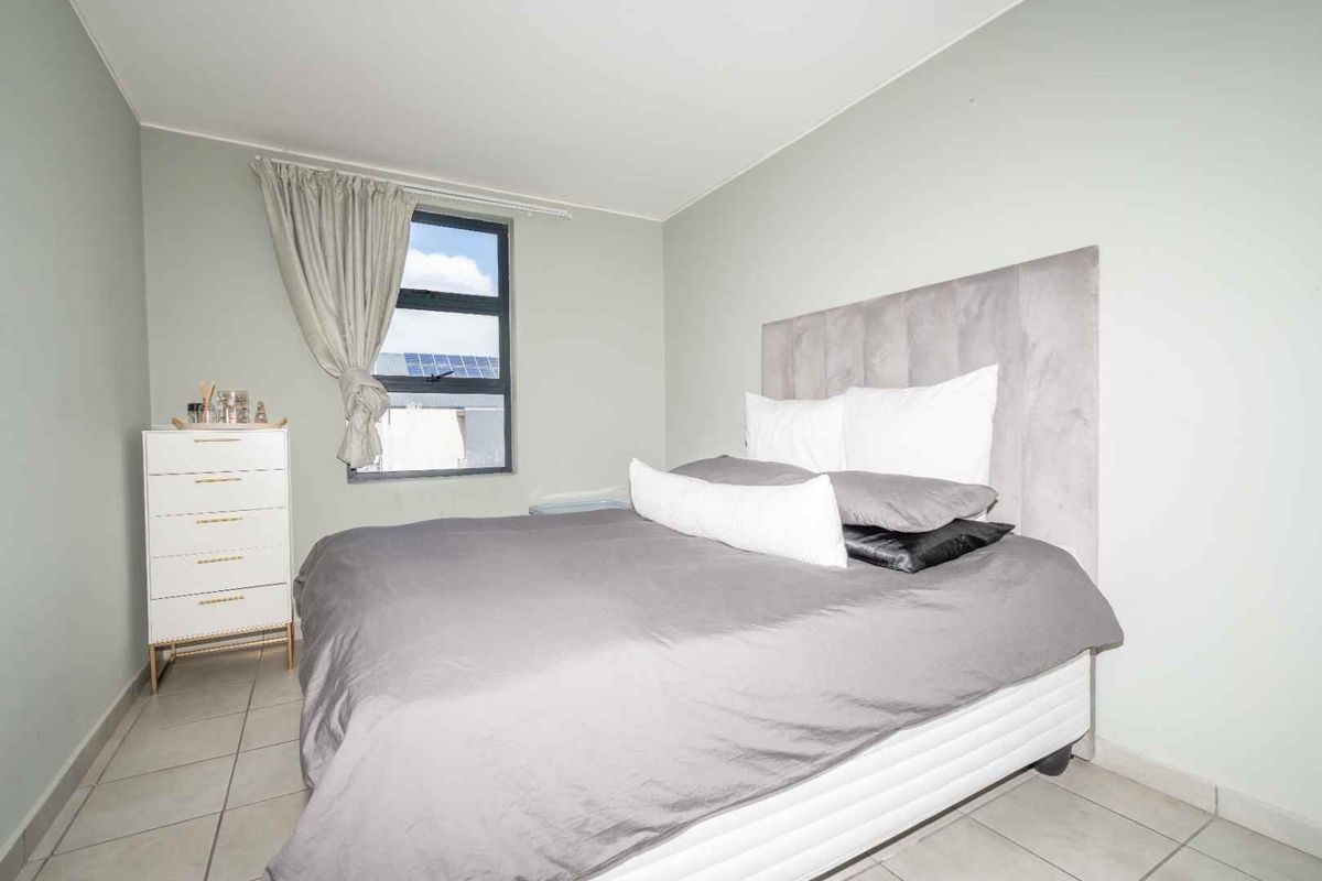 A well-maintained bedroom featuring neutral wall tones, tiled flooring, and a window providing natural light.