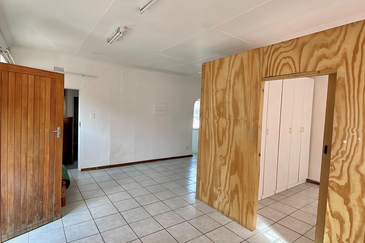 An interior space featuring tiled flooring and a plywood partition wall creating a separate area with built-in cupboards.