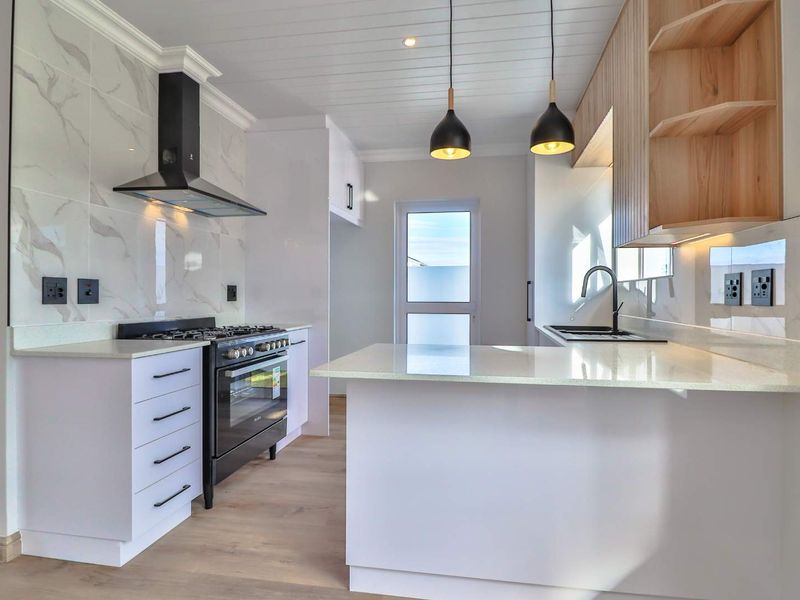 Modern kitchen featuring white cabinetry, marble-look splashbacks, quartz countertops, a gas stove with extractor, and stylish pendant lighting.
