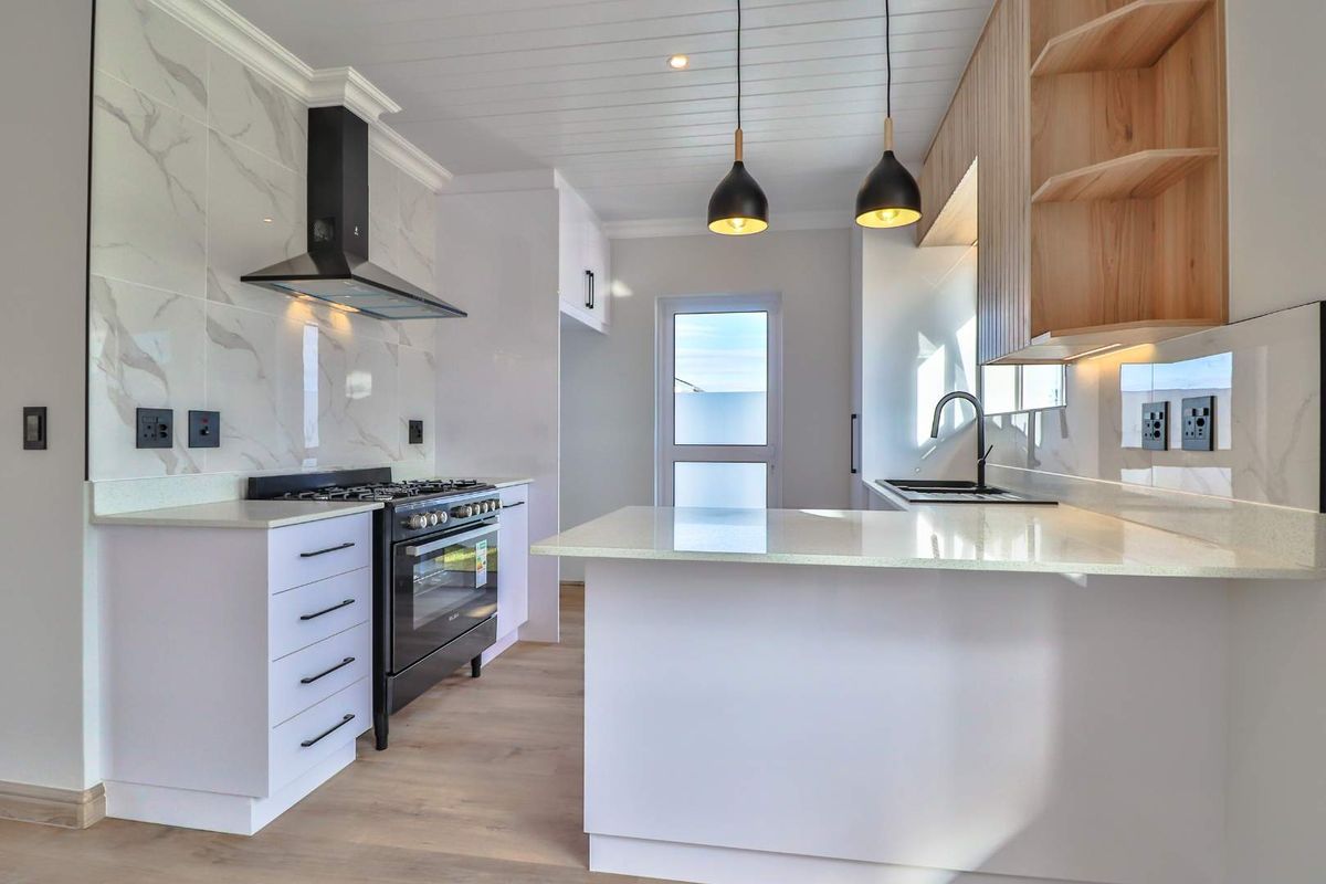 Modern kitchen featuring white cabinetry, marble-look splashbacks, quartz countertops, a gas stove with extractor, and stylish pendant lighting.