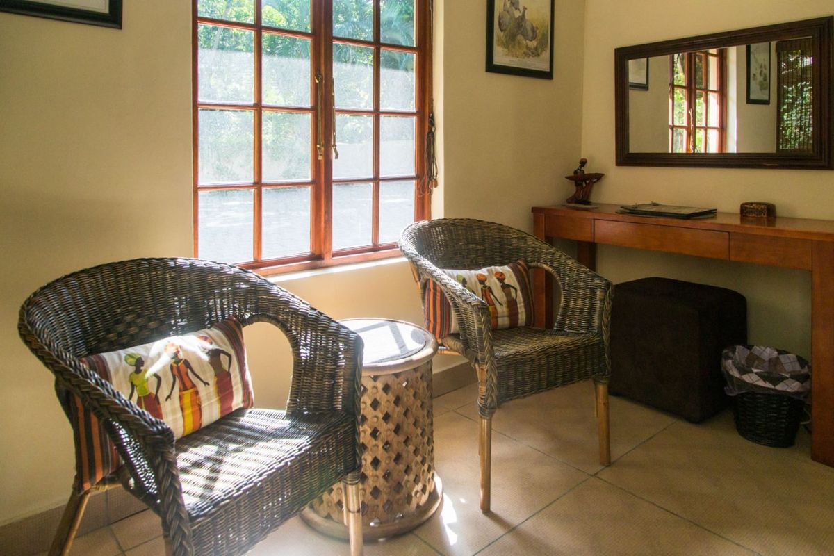 A cozy seating area featuring tiled flooring and a wooden-framed window, providing a comfortable space within the guest house.