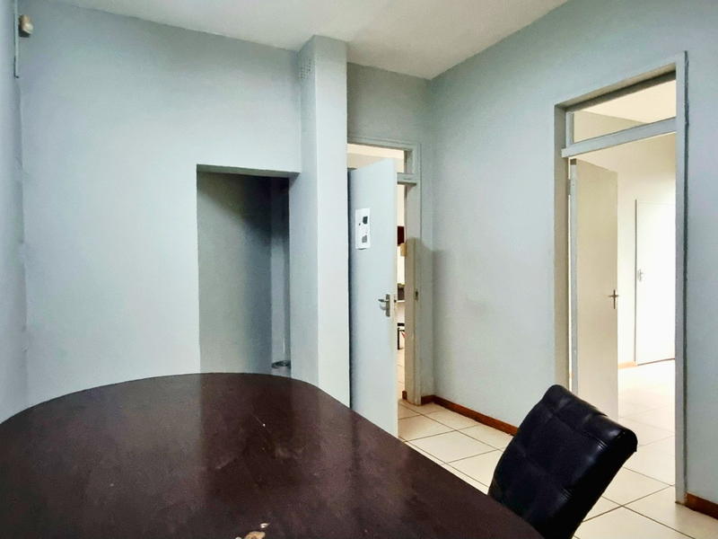 A functional office space featuring tiled flooring and multiple internal access points, suitable for a professional work environment.