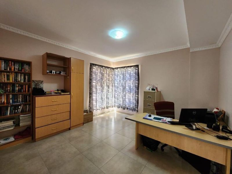 A functional home office space featuring neutral wall tones, tiled flooring, and decorative ceiling cornicing, providing a versatile area for work or study.