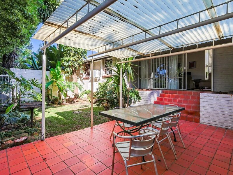 Covered outdoor patio area featuring tiled flooring, brick steps, and direct access to the interior through sliding glass doors.