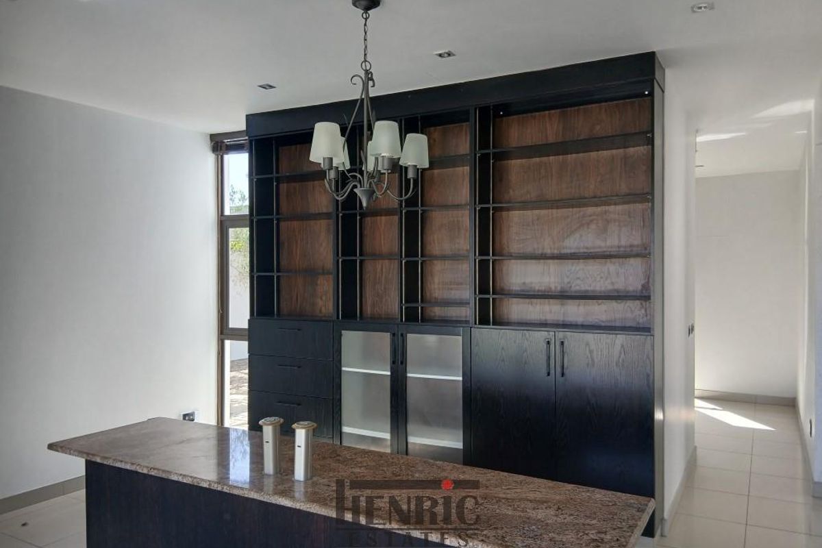 A modern living area featuring a large built-in dark wood cabinetry unit with integrated shelving and a stone-topped island counter.