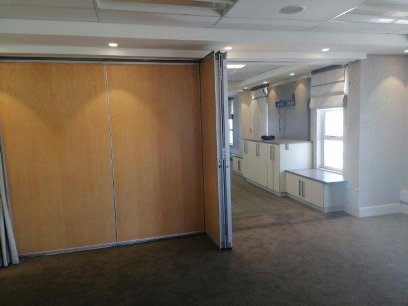 Spacious office area featuring a flexible operable partition wall, built-in storage cabinetry, and recessed ceiling lighting, offering a versatile professional workspace.