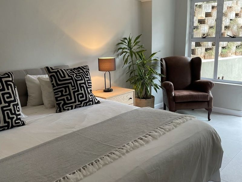 A well-maintained bedroom featuring exposed ceiling beams, tiled flooring, and a wall-mounted air conditioning unit.