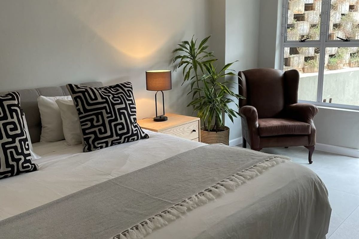 A well-maintained bedroom featuring exposed ceiling beams, tiled flooring, and a wall-mounted air conditioning unit.