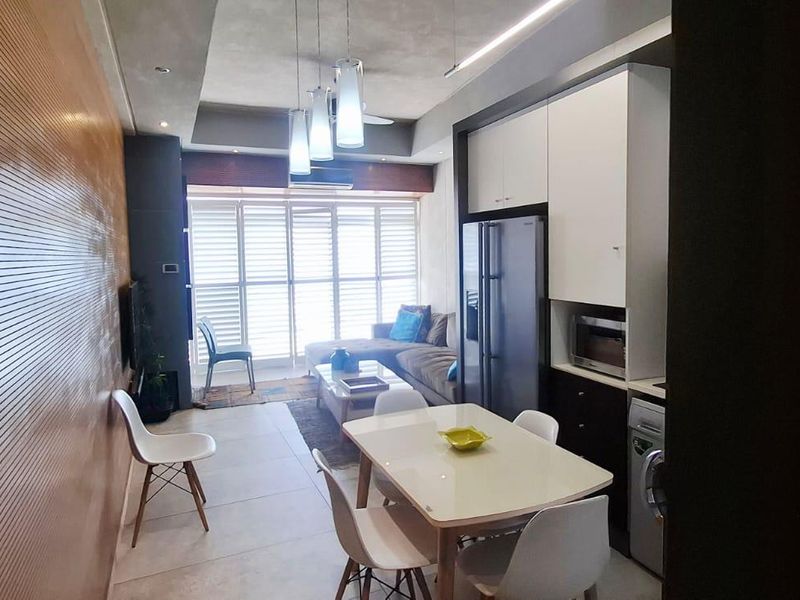 Modern open-plan living and kitchen area featuring sleek cabinetry, recessed lighting, and contemporary tiled flooring, creating a functional and stylish apartment living space.