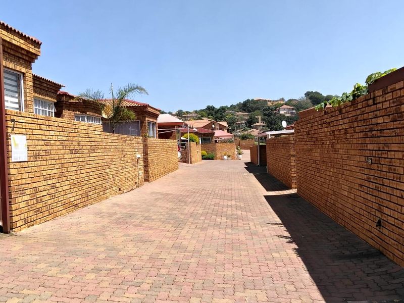A view of the paved driveway and face brick boundary walls within the townhouse complex.