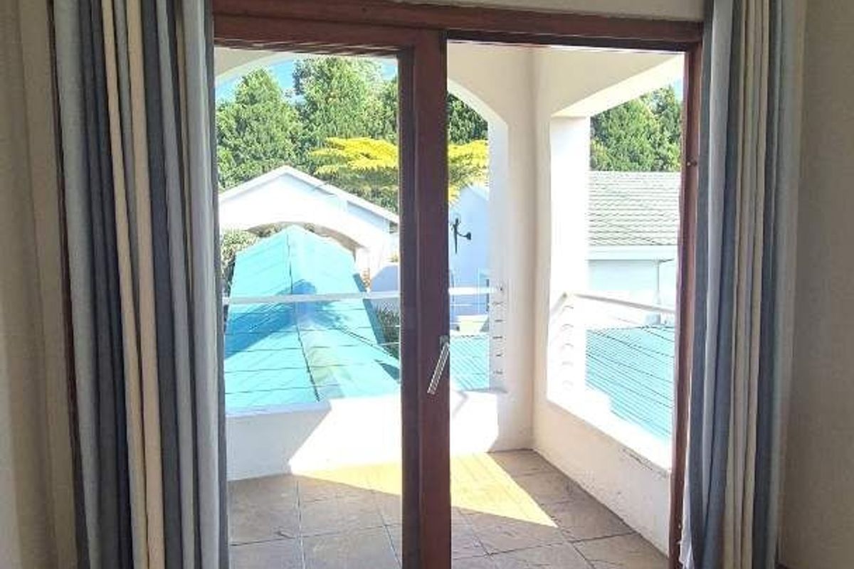 A bright living area featuring large wooden-framed sliding doors that open onto a covered balcony with tiled flooring.