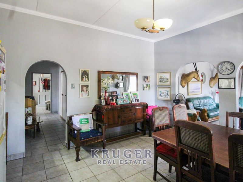 Open plan living and dining area featuring tiled flooring and classic archways connecting to adjacent rooms.