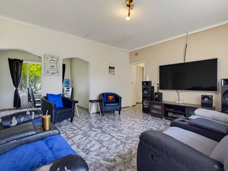 Spacious living room featuring tiled flooring, arched doorways, and coved ceilings, offering a versatile layout for comfortable family living.