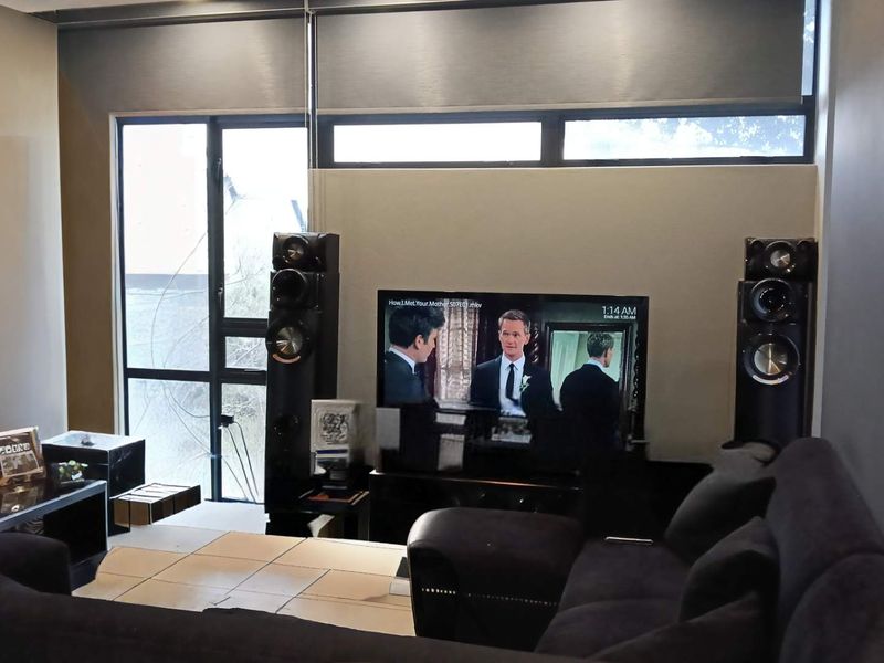 A modern living room featuring large windows with roller blinds, providing ample natural light and a contemporary feel.