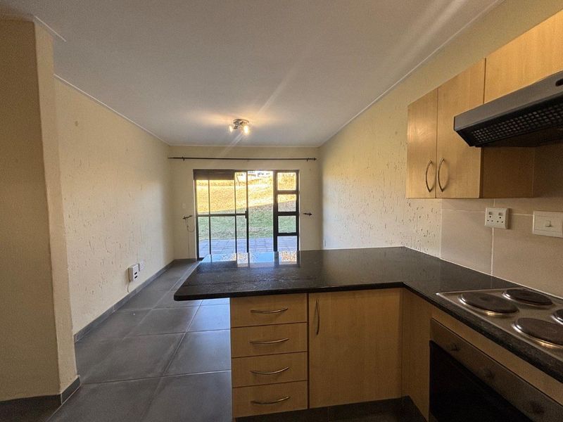 Open-plan kitchen and living area featuring tiled floors, granite countertops, built-in cabinetry, and a sliding glass door leading to an outdoor patio.