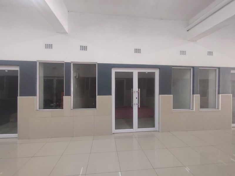 A bright, vacant office space featuring tiled flooring, modern aluminium-framed glass doors, and large windows, offering a clean and professional environment.