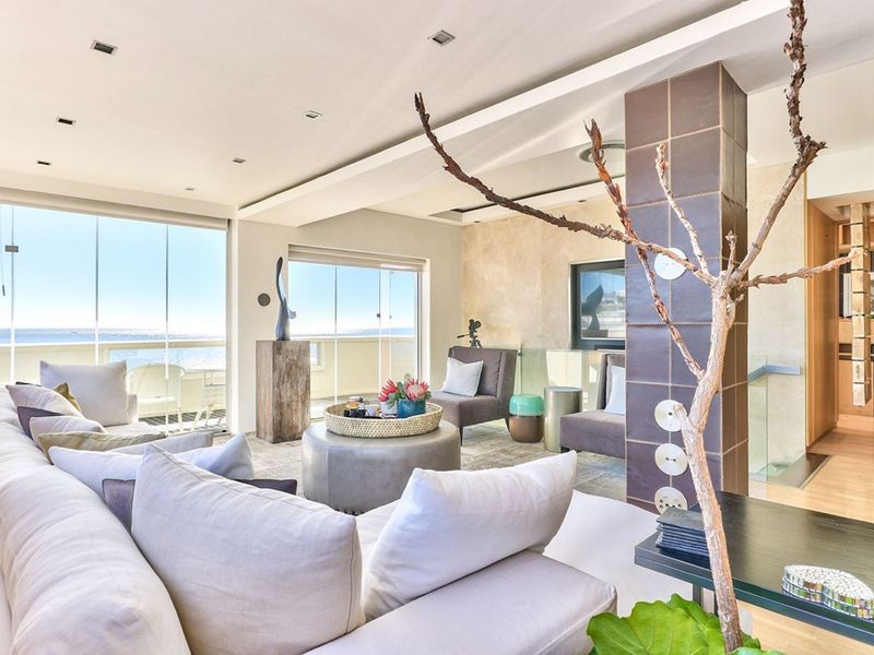 Spacious living area featuring a tiled feature column, recessed lighting, and large glass sliding doors opening to a balcony with ocean views.