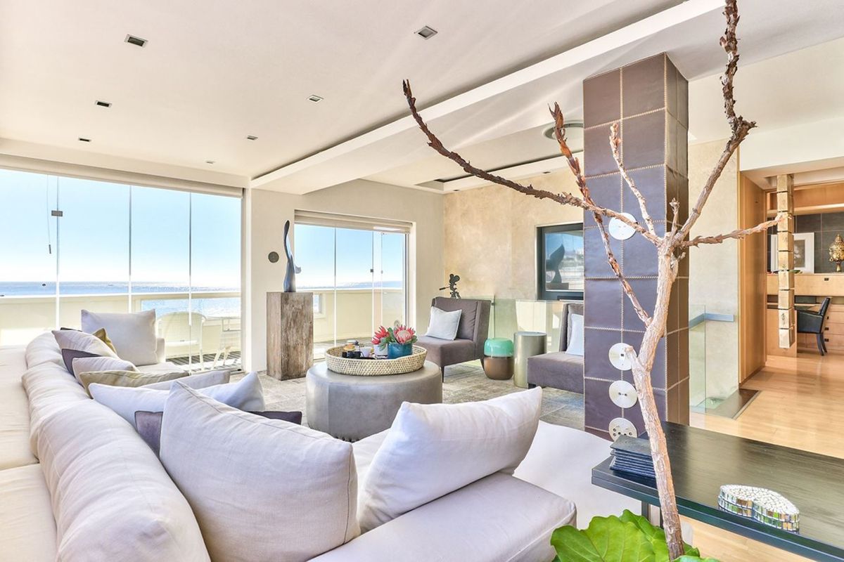 Spacious living area featuring a tiled feature column, recessed lighting, and large glass sliding doors opening to a balcony with ocean views.