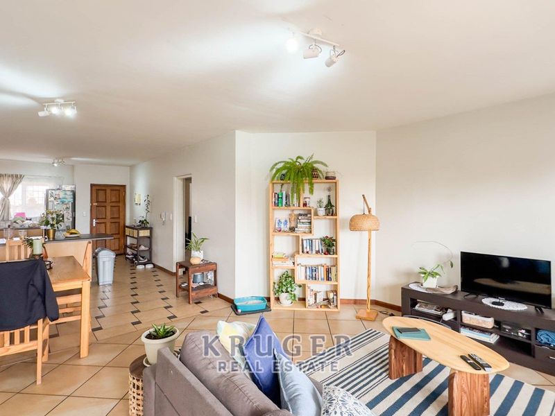 An open-plan living and kitchen area featuring tiled flooring, neutral walls, and functional cabinetry, providing a versatile space for daily living and dining.