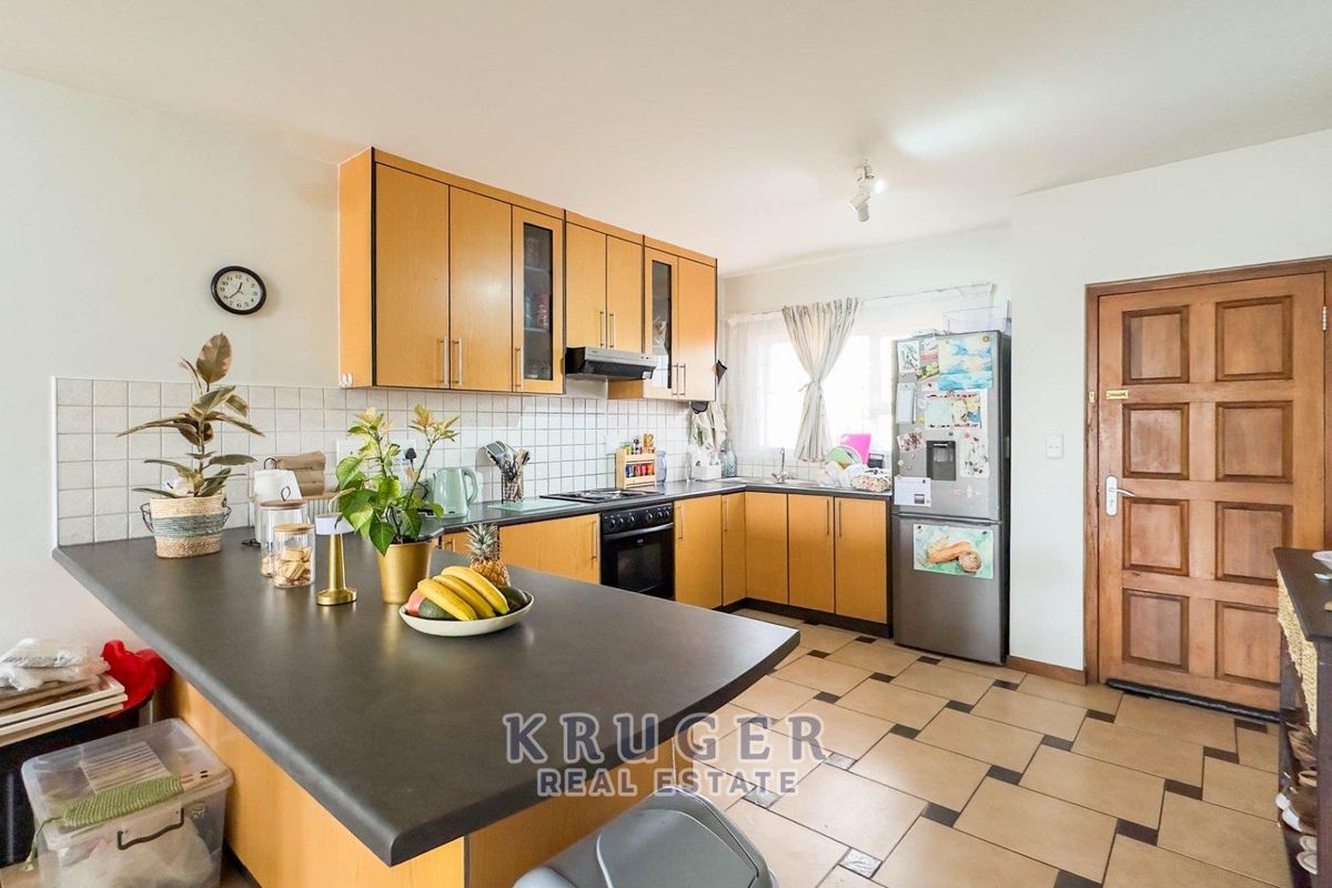 Functional kitchen featuring wooden cabinetry, tiled backsplash, built-in oven with hob, and a breakfast counter, offering a practical layout for daily cooking.
